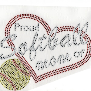 May include: A white fabric patch with a red heart outline and the words "Proud Softball Mom" in silver glitter. A yellow softball with red stitching is in the lower left corner.