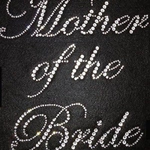 May include: A black fabric background with the words "Mother of the Bride" spelled out in rhinestones.