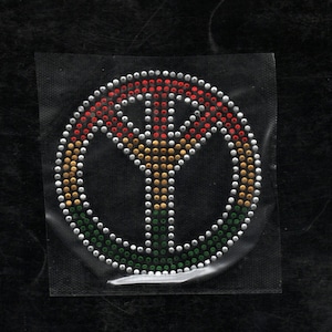 May include: A peace sign made of rhinestones in red, gold, and green colors.