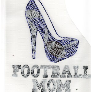 May include: A white mesh design featuring a high-heeled shoe embellished with blue and silver rhinestones. The text "FOOTBALL MOM" is spelled out in silver rhinestones below the shoe. The design is likely for apparel or accessories.