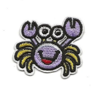 May include: Purple and yellow embroidered iron-on patch of a cartoon crab with a smiling face.