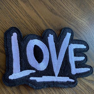 May include: A black felt patch with the word "LOVE" embroidered in white.