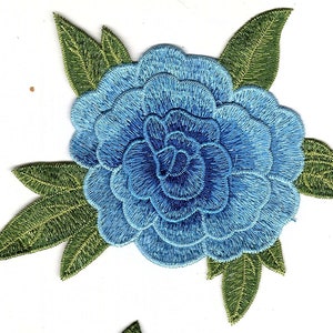 May include: A blue embroidered flower with green leaves. The flower is a single bloom with multiple layers of petals.