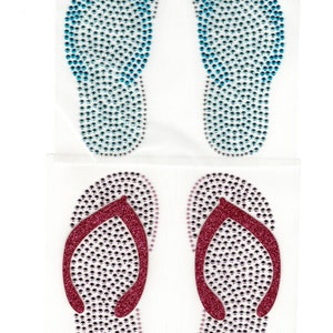 May include: Two pairs of flip-flop shaped iron-on rhinestone embellishments. One pair is blue and the other is pink.