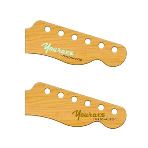 May include: Two unfinished, light brown wood guitar headstocks with the text "Youraxe "Personalized" printed on them. The top headstock has the text in light blue and the bottom headstock has the text in gold.