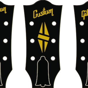 May include: Three black guitar headstock templates with gold lettering and designs. The first template says "Gitturmon Les Paul YOUR TEXT", the second says "Custom" with a diamond design, and the third says "Gitturmon" with a crown design.