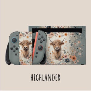 May include: A Nintendo Switch console and controllers with a custom skin featuring a Highland cow and floral design. The controllers are gray with black buttons and a coral-colored rail. The text "HIGHLANDER" is at the bottom.