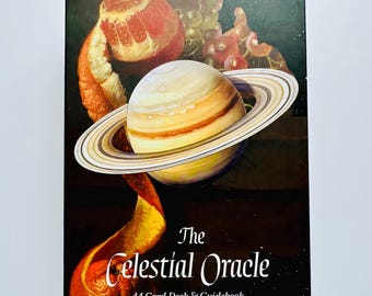 May include: A deck of "The Celestial Oracle" cards and guidebook. The box features a Saturn-like planet with rings, a peeled orange, and grapes against a dark background. The text "The Celestial Oracle" and "44 Card Deck & Guidebook" are displayed.