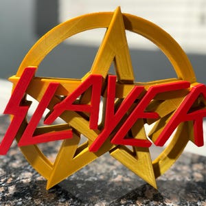 May include: A 3D printed gold pentagram with the word "SLAYER" in red lettering.
