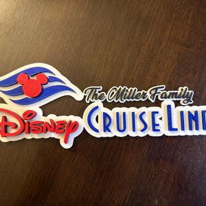 May include: White, blue, and red 3D sign with the text "The Miller Family Disney Cruise Line". The sign features a Mickey Mouse head and the Disney Cruise Line logo.