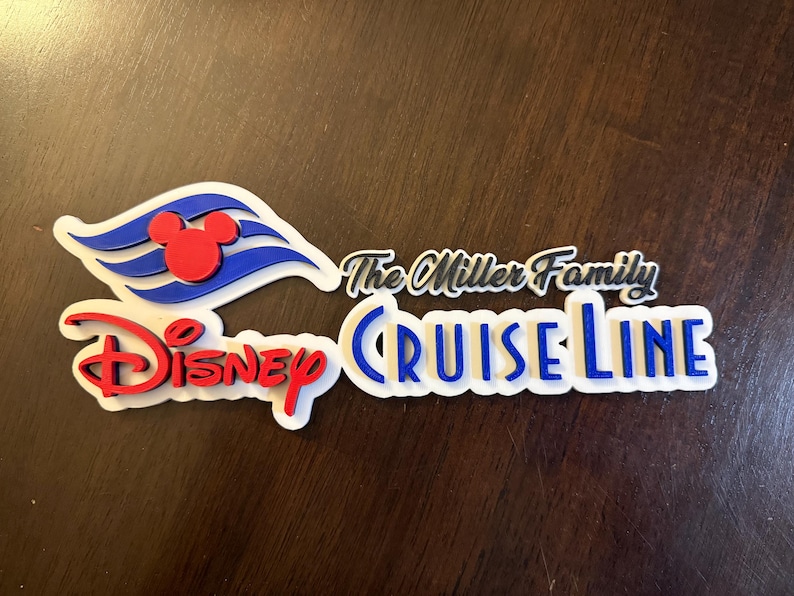 May include: White, blue, and red 3D sign with the text "The Miller Family Disney Cruise Line". The sign features a Mickey Mouse head and the Disney Cruise Line logo.