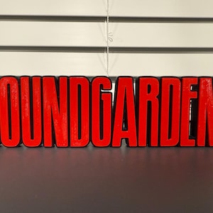 May include: A red and black 3D printed sign with the word "SOUNDGARDEN" in all caps.