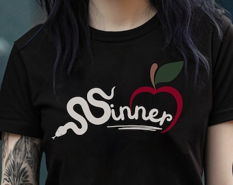May include: Black t-shirt with a white snake and red apple graphic and the text "Sinner".
