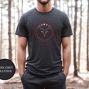 May include: A dark grey heather t-shirt with a graphic of a goat's head inside a circle with moons and stars.