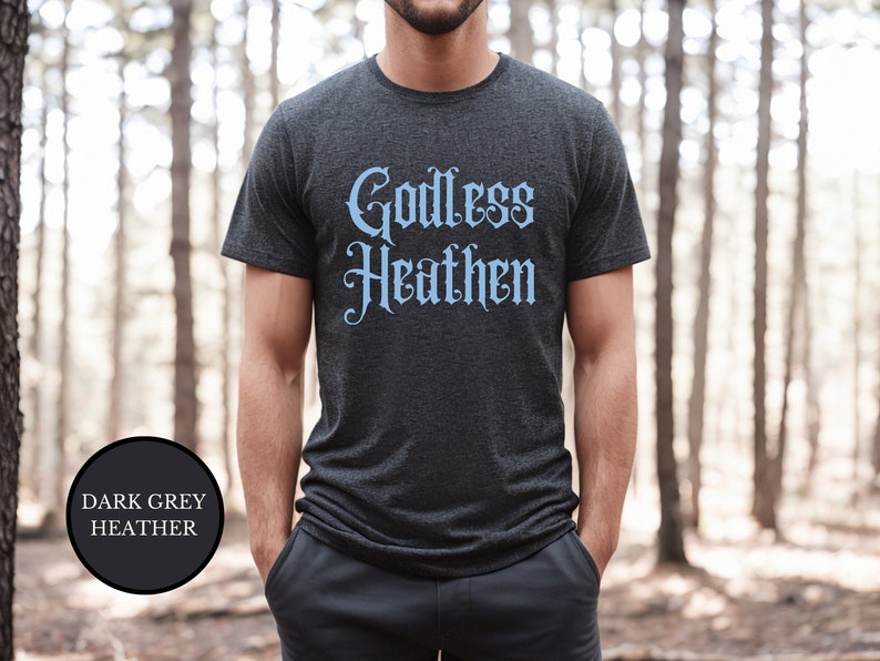 Man in woods wearing an anti religion shirt that says Godless Heathen in gothic pastel blue font on a grey shirt