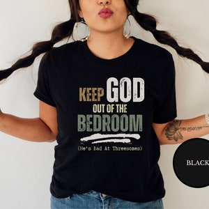 female wiccan witch wearing a Black short sleeve antireligion shirt that says Keep God Out Of The Bed Room - He's Bad At Threeways - Funny pagan blashemous shirt