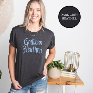 witch girl wearing an anti religion shirt that says Godless Heathen in gothic pastel blue font on a grey shirt
