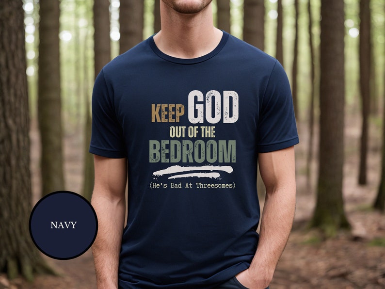 Young Atheist Man wearing a sarcastic anti religion T shirt that says Keep God Out Of The Bed Room - He's Bad At Threeways - funny sexual enuendo shirt for atheists
