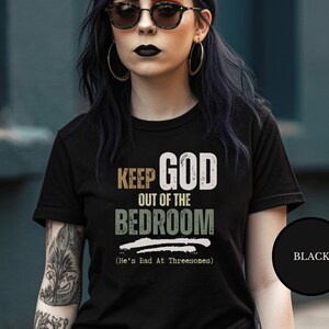 Emo goth with black dyed hair wearing a Black short sleeve antireligion shirt that says Keep God Out Of The Bed Room - He's Bad At Threeways - Funny goth anti god shirt