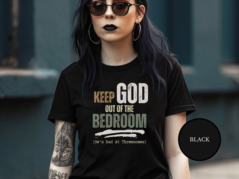 Emo goth with black dyed hair wearing a Black short sleeve antireligion shirt that says Keep God Out Of The Bed Room - He's Bad At Threeways - Funny goth anti god shirt
