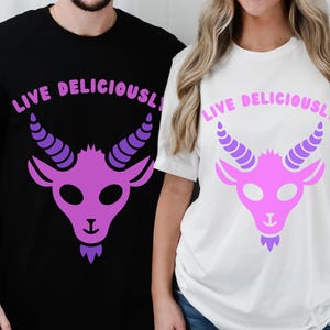 May include: Black and white t-shirts with a purple goat graphic and the text "LIVE DELICIOUSLY". The goat has curved horns and a beard. The shirts are a casual style.