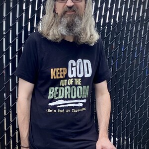 Middle Aged Man at racetrack wearing an anti religion atheist shirt that reads Keep God Out of the Bedroom