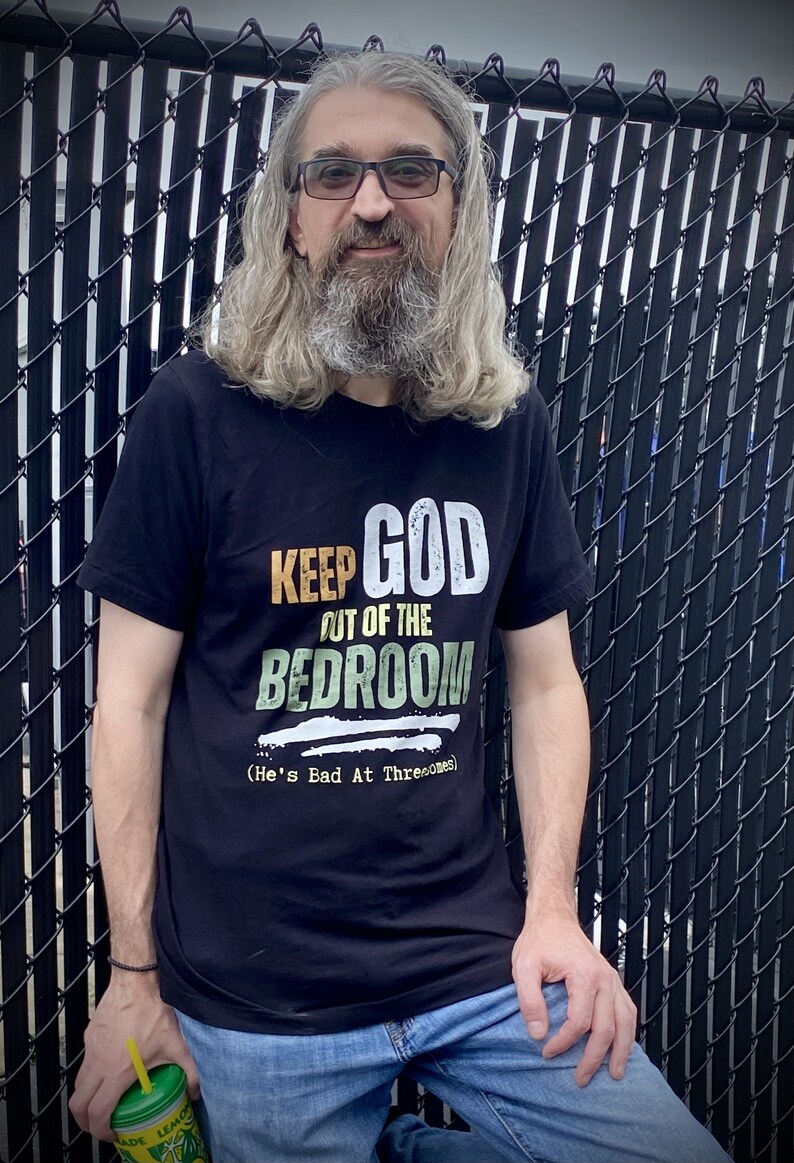 Middle Aged Man at racetrack wearing an anti religion atheist shirt that reads Keep God Out of the Bedroom