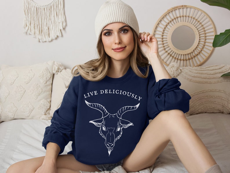 a boho blonde in bed wearing a stockinghat and a navy blue sweatshirt pullover featuring witchcraft and demonic goat Baphomet