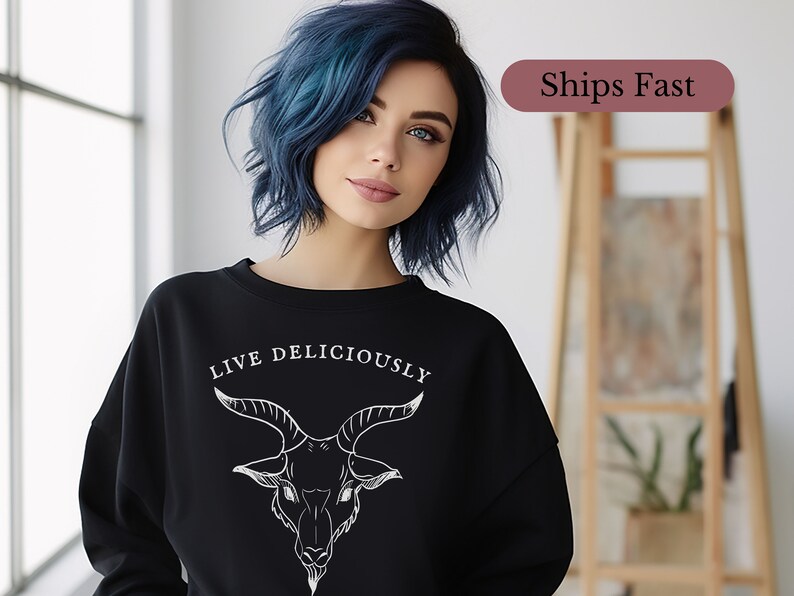 emo goth egirl witch wearing a witchcraft Black Phillip sweatshirt that reads Live Deliciously and features a demonic Baphomet goat head on the front