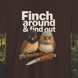 May include: Brown t-shirt featuring two finches perched on a branch, one wearing a black ski mask. The text "Finch around & find out" is printed above the birds. A small knife is below the birds.