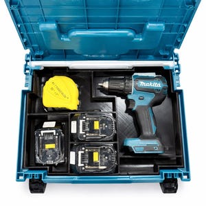 May include: A teal and black Makita cordless drill set in a teal plastic case. The case is open, revealing the drill, two batteries, and a yellow measuring tape. The Makita logo is visible on the drill.