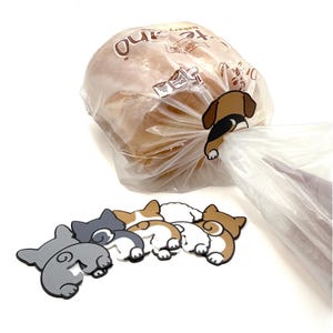 Puede incluir: Una bolsa de plástico transparente con pan se asegura con un clip en forma de perro marrón y negro. Varios clips con forma de trasero de perro en varios colores están debajo. Los clips son para sellar bolsas.