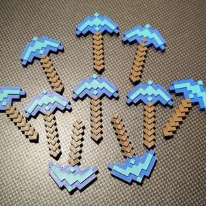 May include: A collection of pixelated pickaxes in shades of blue and brown. The pickaxes are arranged in a scattered pattern, with the heads of the tools in a lighter blue and the handles in a darker brown.