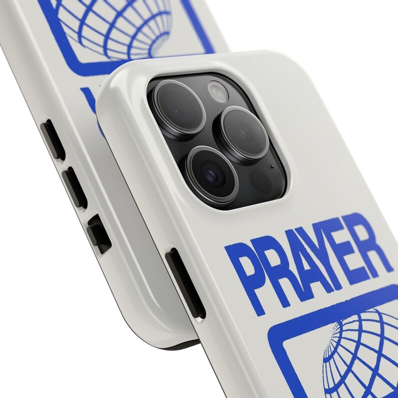 May include: White iPhone case with a blue "PRAYER" text and a globe graphic. The case has a raised camera bump with three lenses.