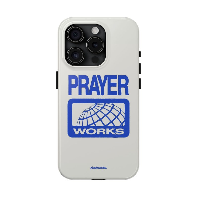 May include: White iPhone case featuring a blue graphic that reads "PRAYER WORKS" and a globe icon. The case has a black camera bump and a black border.