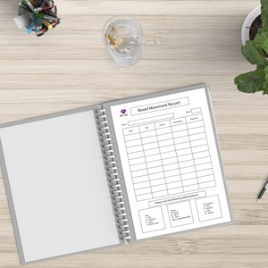 May include: A white binder with a spiral binding, open to a page titled "Bowel Movement Record". The page has a table with columns for date, time, color, consistency, and special notes. There is also a section for "Please use the following abbreviations".