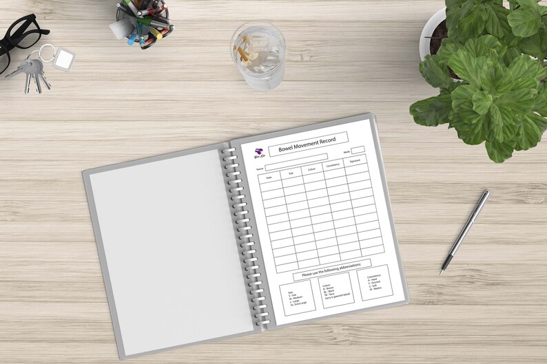 May include: A white binder with a spiral binding, open to a page titled "Bowel Movement Record". The page has a table with columns for date, time, color, consistency, and special notes. There is also a section for "Please use the following abbreviations".