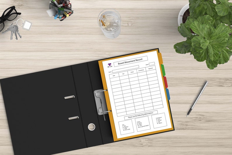 May include: A black binder with a yellow tab divider and a white sheet of paper with the title "Bowel Movement Record". The sheet has columns for date, time, consistency, and other observations.