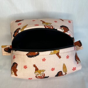 Puede incluir: Una bolsa rosa con cremallera, con una cremallera negra y un estampado de un personaje de dibujos animados. La bolsa est&aacute; abierta y el interior es negro.