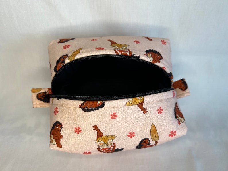 Puede incluir: Una bolsa rosa con cremallera, con una cremallera negra y un estampado de un personaje de dibujos animados. La bolsa est&aacute; abierta y el interior es negro.