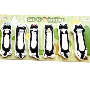 May include: A set of six cat-shaped sticky notes with black and white markings, each in a different pose. The notes are on a light green background with the text "Cat Is Resting" and "180PCS".