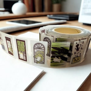 May include: A roll of adhesive tape featuring a repeating series of rectangular illustrations. Each segment depicts a small white cat in various scenes, including sitting in arched windows with sunflowers, lounging in green foliage, and playing with small objects.