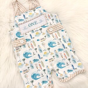 the big one first birthday boy romper my first wave summer beach surfer aqua blue tan white gingham yellow smash cake outfit overalls, ONE smocked romper first birthday beach party surfing, ocean embroidered smocked spring summer 1st birthday boy outfit romper baby boys
