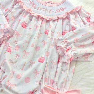 pink bow first birthday girl romper pink and white outfit, pink white smocked bubble romper first birthday winter bows ruffle bows  embroidered smocked long sleeve 1st birthday outfit romper baby girls the mod mango baby boutique