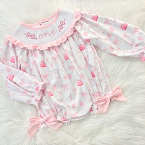 pink bow first birthday girl romper pink and white outfit, pink white smocked bubble romper first birthday winter bows ruffle bows  embroidered smocked long sleeve 1st birthday outfit romper baby girls the mod mango baby boutique
