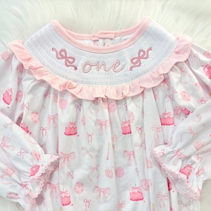 pink bow first birthday girl romper pink and white outfit, pink white smocked bubble romper first birthday winter bows ruffle bows  embroidered smocked long sleeve 1st birthday outfit romper baby girls the mod mango baby boutique