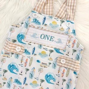 the big one first birthday boy romper my first wave summer beach surfer aqua blue tan white gingham yellow smash cake outfit overalls, ONE smocked romper first birthday beach party surfing, ocean embroidered smocked spring summer 1st birthday boy outfit romper baby boys cake smash outfit, the mod mango baby boutique co