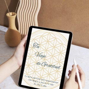 Könnte beinhalten: Ein digitales Tablet zeigt ein geführtes Tagebuch zum Üben von Dankbarkeit. Der Bildschirm zeigt ein geometrisches Muster und den Text "Tu Viaje de Gratitud" auf Spanisch, was mit "Deine Reise der Dankbarkeit" übersetzt wird. Der Text darunter lautet "Tu dano personal para experimentar mas alegria y paz en tu vida en solo 21 dias", was mit "Dein persönlicher Leitfaden, um mehr Freude und Frieden in deinem Leben zu erfahren, in nur 21 Tagen" übersetzt wird.