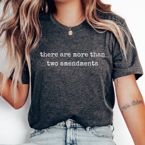 Puede incluir: Una camiseta gris oscuro con el texto "there are more than two amendments" impreso en blanco.