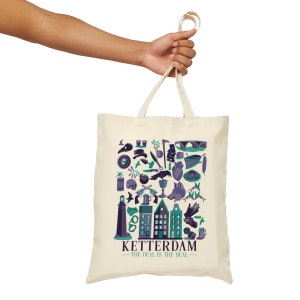 May include: Cream tote bag with a collection of teal, purple, and green illustrated icons. The bag features the text "KETTERDAM" and "THE DEAL IS THE DEAL" in teal. The bag is held by a hand.